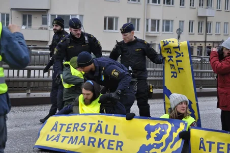 Aktivister från Återställ Våtmarker som blockerar en gata med poliser i bakgrunden