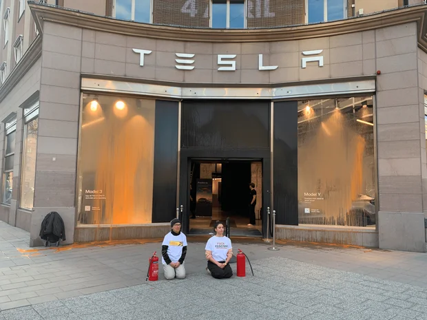 Aktivister från Återställ Våtmarker knäande framför Tesla butik i Stockholm efter aktionen.