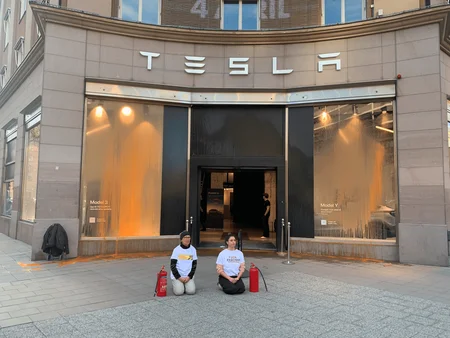 Aktivister från Återställ Våtmarker knäande framför Tesla butik i Stockholm efter aktionen.