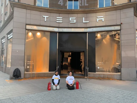 Activists from Återställ Våtmarker kneeling in front of the Tesla store in Stockholm after the action.