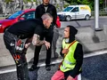 Sittande aktivist som blockerar en gata och lyssnar till en bilist.