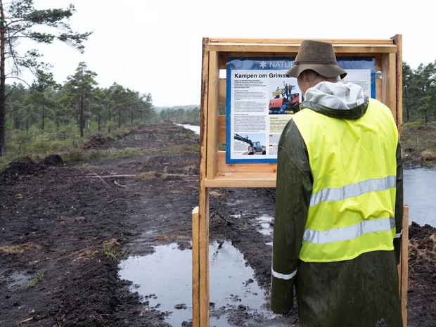 Människa tittar på informationsskylt av det olydiga naturreservatet i Grimsås
