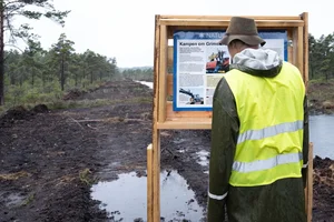 Människa tittar på informationsskylt av det olydiga naturreservatet i Grimsås