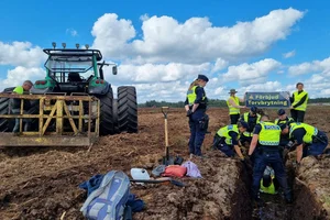 Polisen lyfter upp en aktivist som har lagt sig i en dike, i bakgrunden en banner med "Förbjud torvbrytning"