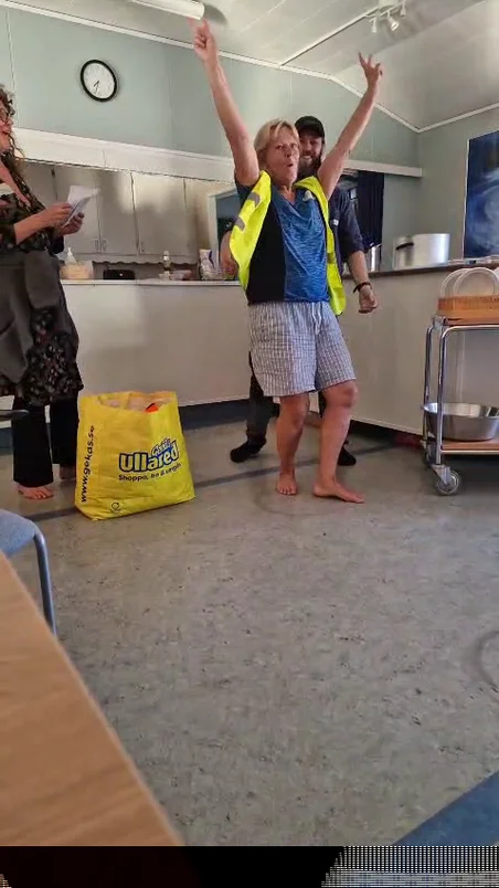 Glad människa med gul varn-västa som räcker armarna i luften
