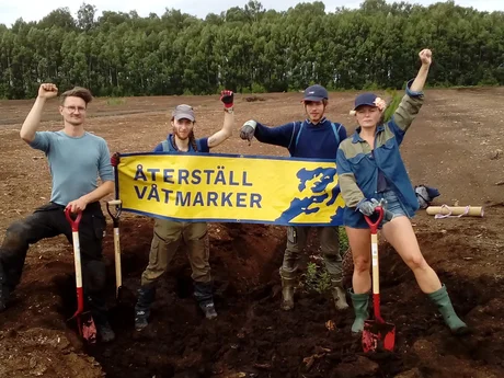Unga människor på en torvbrott med en banner.