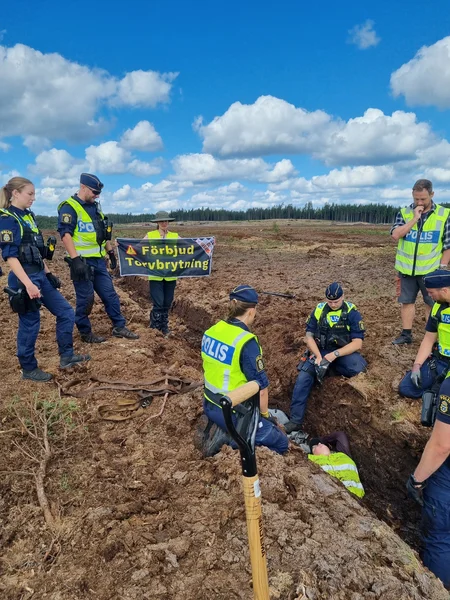 Grupp av poliser griper en aktivist från Återställ Våtmarker som ligger i en dike