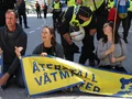 Energetiska människor som protesterar för återställning av våtmarker med en blockad av en gata, en polisman pratar med en av aktivisterna.
