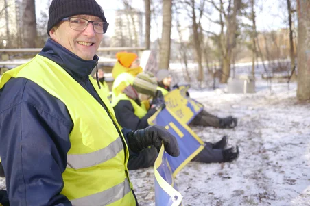 Person på en aktionsträning som håller en banner från Återställ Våtmarker och titta leende i kameran.