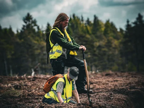 Two people from Återställ Våtmarker digging a ditch at the peat extraction site at Grimsås.