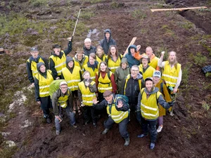 Grupp av människor med gula västor på en mosse i aktion mot torvbrytning, fotograferad från en drönare