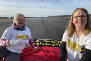 Två kvinnor som sitter på landningsbana av Sundvalls flygplats som demonstration mot torvbrytning i Sverige.