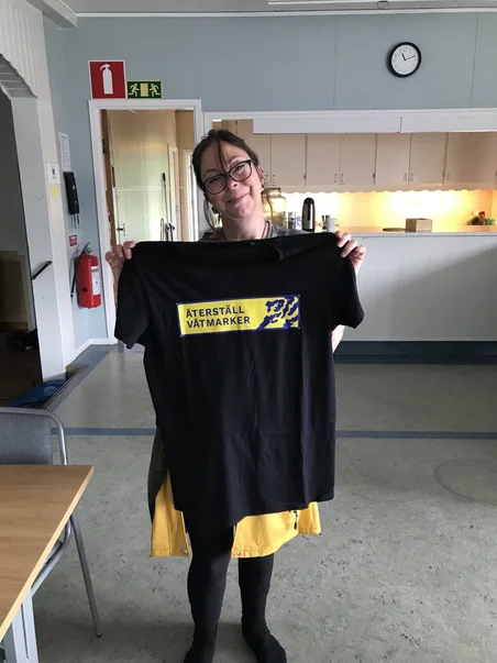 En månadsgivare med en Återställ Våtmarker shirt