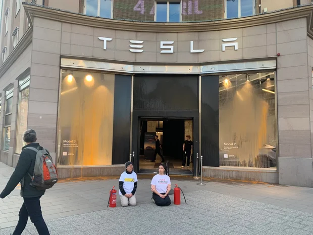 Två aktivister från Återställ Våtmarker sprayade Teslabutiken i Stockholm och väntar efter aktionen på polisen.
