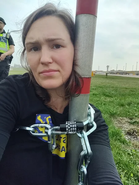 Aktivist från Återställ Våtmarker på Malmö Airport, fastlåst på en stolpe via en kedja.