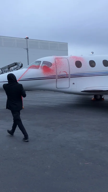 Aktivist från Återställ Våtmarker som sprayar en privatjet med röd (vattenlöslig!) färg med hjälp av en brandsläckare.. 