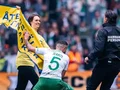 Aktivist springer med en banner på fotballsplan under cupfinalen 2022.