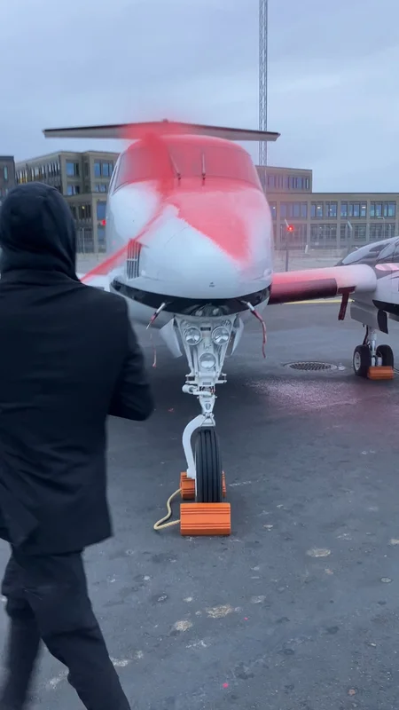 Aktivist från Återställ Våtmarker som sprayar en privatjet med röd (vattenlöslig!) färg. 