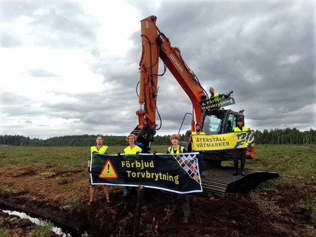 Flera människor som blockerar en baggare på en klimatskadlig torvbrott.