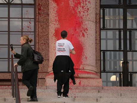 Aktivist som färgar en pelare av buggnaden av Finnslands parlament med röd färg.