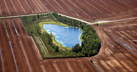 Flygbild av en torvbrott med en liten bit levande våtmark i stark kontrast av livlös torvbrott.