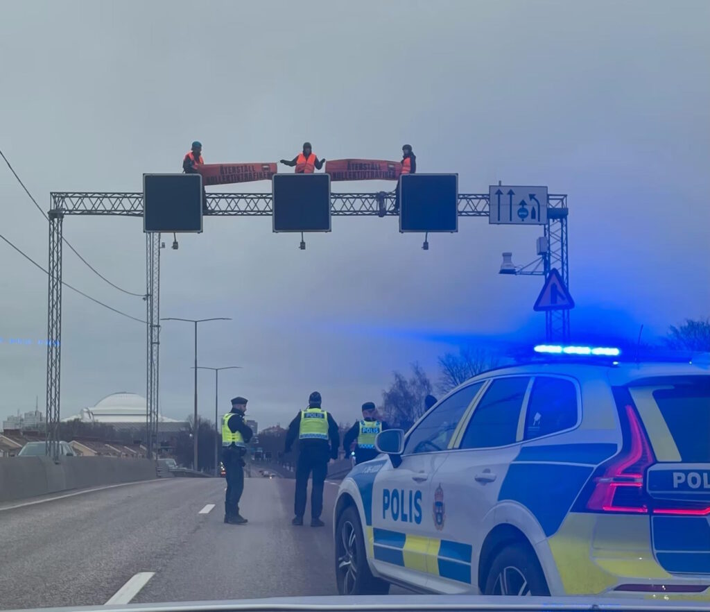 Aktivister klättrade upp på balk över motorvägen.